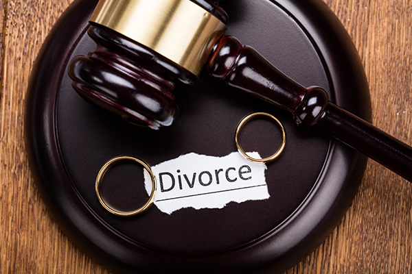 Gavel, sound block, two wedding rings, and a torn paper with "Divorce" written on it.